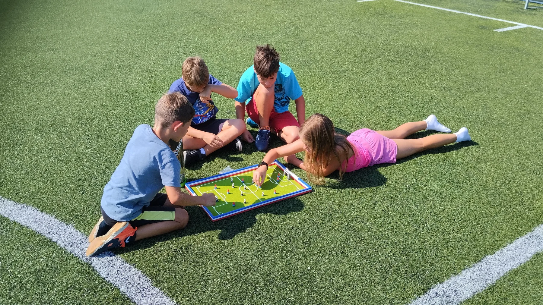 Kinder spielen Footballec draußen auf einem Sportplatz